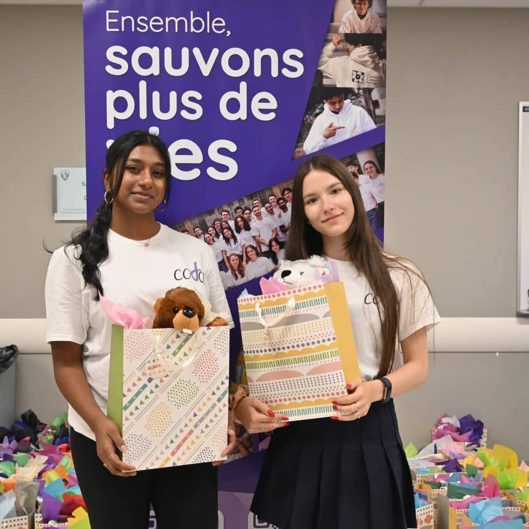 Deux de nos bénévoles entourés de sacs-cadeaux lors de notre événement Noël en juillet